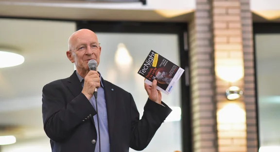 Claude Nicolier hält Mikrofon und Buch bei Veranstaltung