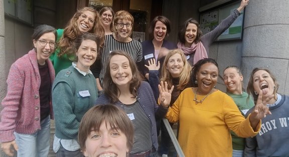 Gruppe fröhlicher Frauen posiert vor einem Gebäude